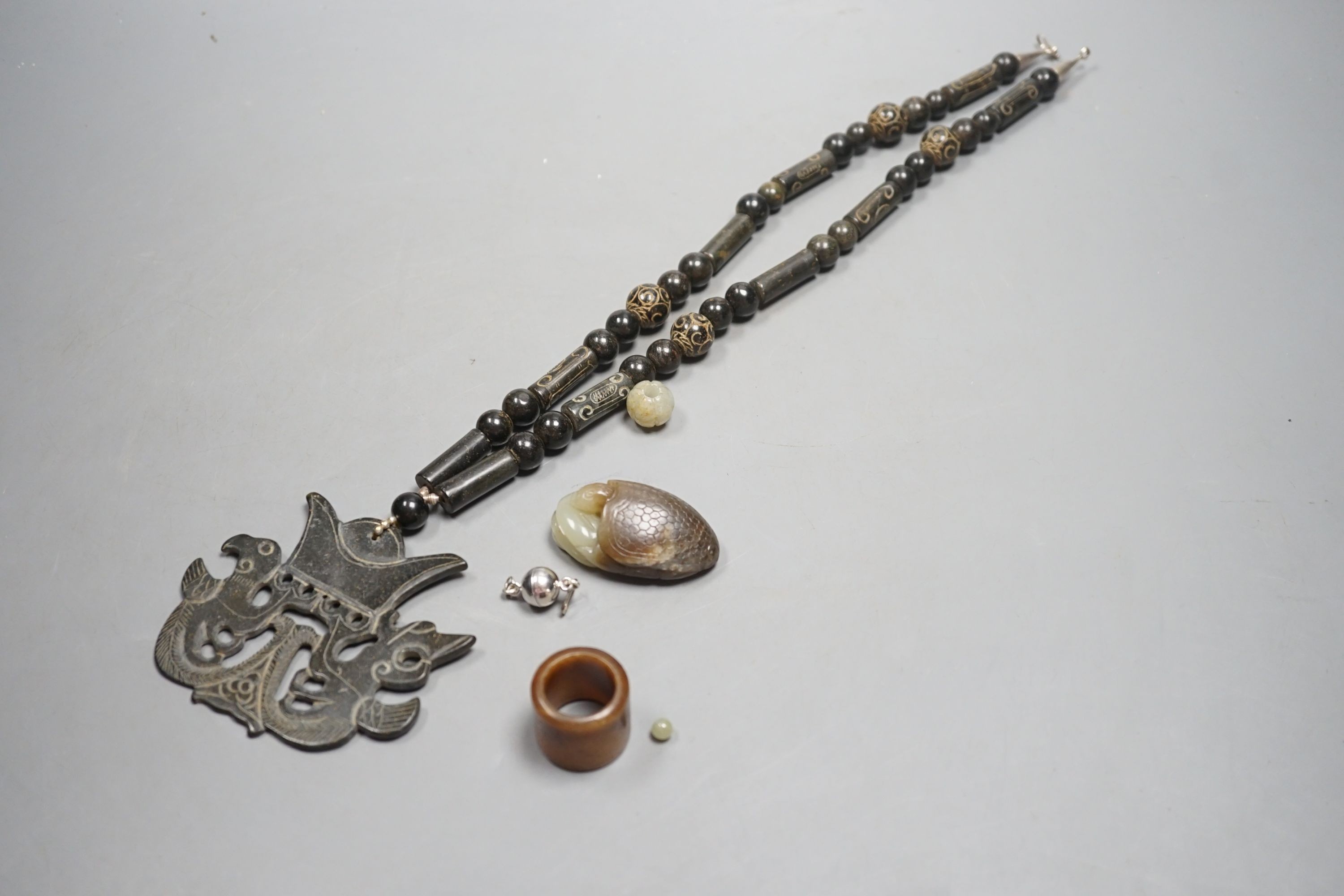 Kai Yin Lo of Hong Kong, a jade turtle and snake pendant, jade archer’s ring and two beads, formerly strung on a necklace together with a hardstone necklace